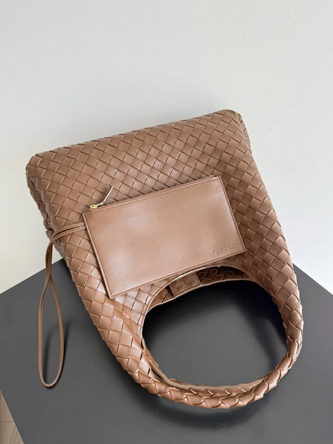 Batch 2760 new products are coming! BOTTEGA VENETA Bottega Veneta's 2025 new Campana shoulder bag is on the market~ First of all, I would like to praise the weight of this bag. As a not too small bag, it is very light for daily use. For people like me who need to carry a lot of belongings when going out, this advantage is great, and it greatly reduces the burden of traveling. 🛍️The shape is a bit like a combination of parachute and jodie. The blunt triangle shape is cute and honest. Carrying it on your back when going shopping is a good mood accelerator. The handles and body of the bag are both classic weaves. A tie is added to the original open design. If it is not tied up, the bag will look like a small vegetable basket when carried. Style number: 844250 Size: 39*24*18.5cm